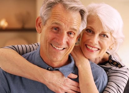 An older couple smiling and hugging.