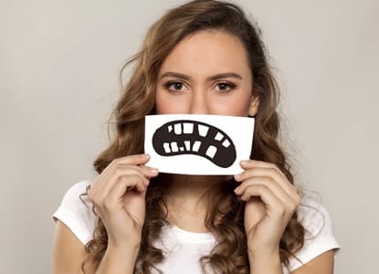 A woman holding a picture of a damaged mouth.