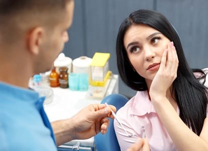 A woman with tooth pain listening to a dentist.