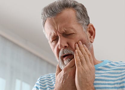 Older man holding jaw in pain