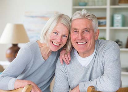 senior couple smiling and wearing matching gray sweaters