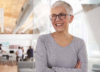 senior woman smiling while crossing her arms and looking off into the distance