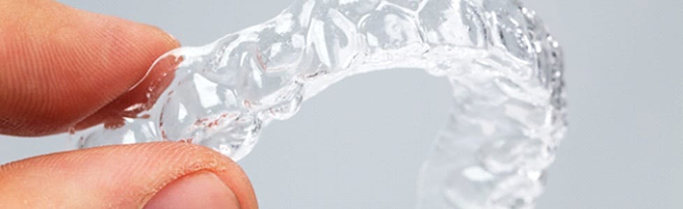 A person holding a clear aligner.