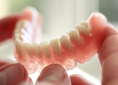 Hand holding a full denture